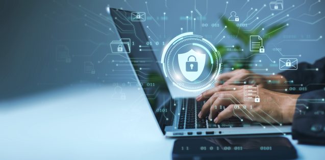 A businessman works on his laptop at home with a virtual display showing a symbol to signify cyber security privacy and online data protection.